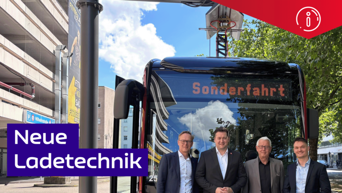 Vier Männer in Anzügen stehen vor einem Bus. In dessen Zielfilm steht Sonderfahrt